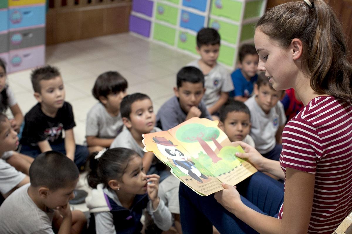 Projects Abroad volunteer reads a story book as a volunteer with children in Costa Rica Volunteer opportunities include reading books with children in Costa Rica